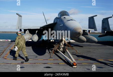 Ein Besatzungsmitglied geht auf dem Flugdeck der USS Gerald R. Ford, dem „größten Kriegsschiff der Welt“, während eines Medienbesuchs an einem F18-Jet vorbei, während es während eines Zwischenstopps in Portsmouth im Solent vor Anker liegt. Bilddatum: Donnerstag, 17. November 2022. Stockfoto