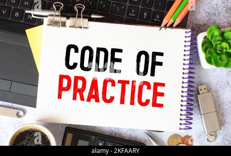 Code of Practice Text auf einem Notizbuch mit Bleistiften geschrieben. Stockfoto