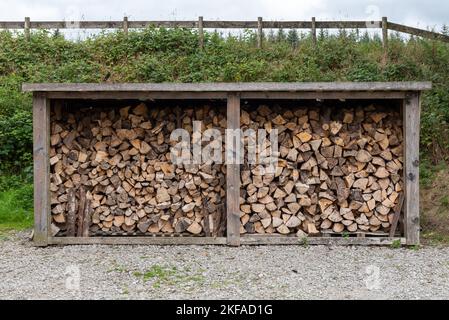 Großer Aufbewahrungsbehälter aus Holz mit aufgeschnittenen Holzstücken, die innen trocknen. Gehackte Holzstämme, um Brennstoff für die Verbrennung in einem Holzfeuer zu machen. Stockfoto
