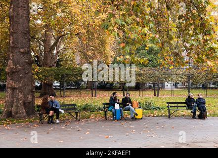 Russell Square London; Menschen sitzen im Herbst auf Bänken am Russell Square, Bloomsbury London, Großbritannien Stockfoto