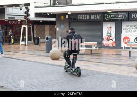 Mann, der einen Elektroroller auf dem Bürgersteig im Stadtzentrum von Burnley fährt. Stockfoto