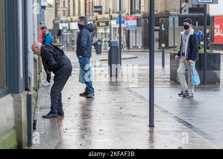 Menschen, die an Geldautomaten Schlange stehen und Geld abheben. Das Tragen von Masken aufgrund von Coronaviren. Stockfoto