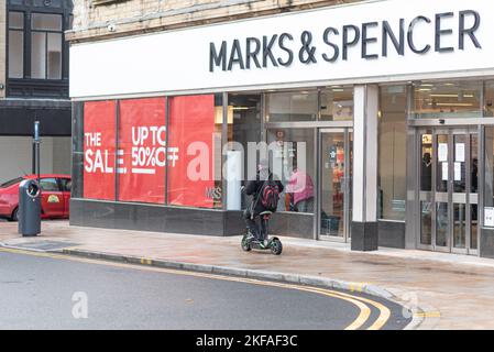 Mann, der einen Elektroroller auf dem Bürgersteig vor Marks and Spencers im Stadtzentrum von Burnley fährt. Stockfoto