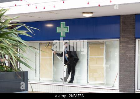 Mann putzt Fenster in der Apotheke Boots. Männer arbeiten. Fensterputzer. Stockfoto