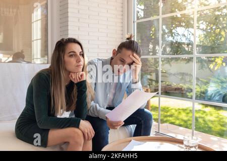 Verzweifeltes junges Paar hat kein Geld, um Schulden zu bezahlen, Miete für Wohnung zu bezahlen. Halten Kopf, kann keine Rechnungen bezahlen, mit finanziellen Schwierigkeiten. Haushalt Stockfoto