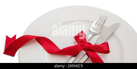 Feiertagstabelle Einstellung Nahaufnahme. Besteck und rote Satinband Dekoration auf weißem Geschirr, Weihnachten, Valentinstag Feier Abendessen Stockfoto