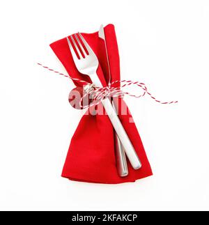 Weihnachtsfeiertage Tischkulisse, Festessen. Besteck, rote Stoffserviette und Kordelbogen isoliert auf weiß, Stockfoto