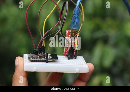 Mikrocontroller-Platine mit anderen elektronischen Komponenten, die als Prototyp einiger elektronischer Projekte auf einer in der Hand gehaltenen Platine hergestellt wurden Stockfoto