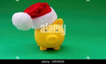 Weihnachtsangebot. Sparschwein mit Weihnachtsmütze isoliert auf grünem Hintergrund. Stockfoto