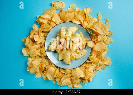 Schädliche Lebensmittel. Gebratene Kartoffeln und Pommes auf blauem Hintergrund. Frittierte Lebensmittel sind schlecht für Ihre Gesundheit Stockfoto