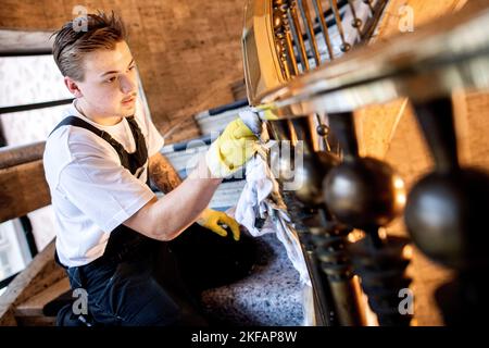 17. November 2022, Bremen: Luc Lamer aus Bayern, Teilnehmer des nationalen Wettbewerbs im Bereich Gebäudereinigung, reinigt im Haus des Reiches ein Treppengeländer aus Messing. Beim jährlichen Wettbewerb treten Gesellen aus mehreren deutschen Bundesländern in verschiedenen Disziplinen der Gebäudereinigung gegeneinander an. Foto: Hauke-Christian Dittrich/dpa Stockfoto