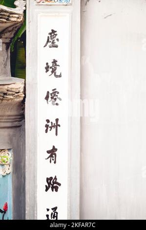 Eine vertikale Aufnahme der alten chinesischen Schrift auf einem weißen buddhistischen Tempel Stockfoto