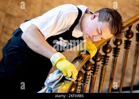 Bremen, Deutschland. 17.. November 2022. Luc Lamer aus Bayern, ein Teilnehmer des nationalen Wettbewerbs in der Gebäudereinigung, reinigt im Haus des Reiches ein Treppengeländer aus Messing. Beim jährlichen Wettbewerb treten Gesellen aus mehreren deutschen Bundesländern in verschiedenen Disziplinen der Gebäudereinigung gegeneinander an. Quelle: Hauke-Christian Dittrich/dpa/Alamy Live News Stockfoto