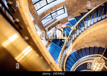 Bremen, Deutschland. 17.. November 2022. Luc Lamer aus Bayern, ein Teilnehmer des nationalen Wettbewerbs in der Gebäudereinigung, reinigt im Haus des Reiches ein Treppengeländer aus Messing. Beim jährlichen Wettbewerb treten Gesellen aus mehreren deutschen Bundesländern in verschiedenen Disziplinen der Gebäudereinigung gegeneinander an. Quelle: Hauke-Christian Dittrich/dpa/Alamy Live News Stockfoto