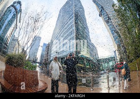 Spiegelungen hoher Gebäude auf der von Regen gespritzten polierten Oberfläche eines öffentlichen Kunstwerks in Canary Wharf, London, Großbritannien Stockfoto