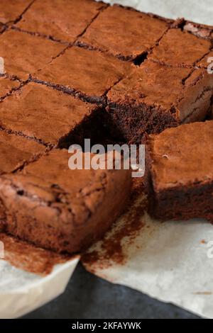 Hausgemachte leckere Schokoladenbrownies, frisch aus dem Ofen, in Quadrate geschnitten und ein Stück bewegt, um die innere Textur der Brownies zu zeigen Stockfoto