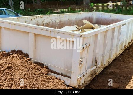 Im Rahmen des Abfallentsorgungsverfahrens auf der Baustelle wird ein Metallbehälter zum Recycling von Müllabfällen verwendet Stockfoto