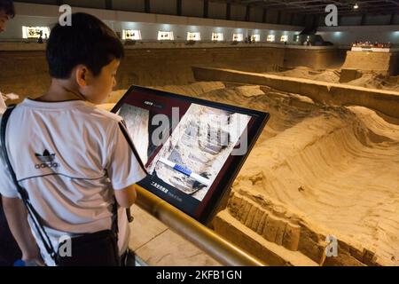 Tourist Kind Kind Kind beim Betrachen und Lesen des Informationszeichens in Chinesisch und Englisch, das die Krieger Figuren beschreibt, aus chinesischem Terrakotta Ton, in Pit 2. Die Terrakotta-Armee im Mausoleum-Museum von Kaiser Qinshihuang in Xi'an, China. VRC. (125) Stockfoto