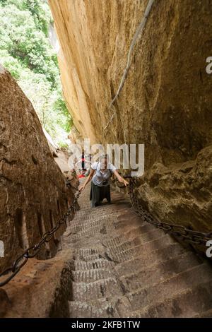 Eine westeuropäische Touristin klettert steile Stufen hoch, die in den Steinboden eines schmalen Passes auf dem Huashan Mountain / Mount Hua / Mt Hua in der Nähe von Huayin, Weinan, China, VR China gehauen und geschnitzt wurden. (125) Stockfoto