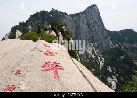 Ausblicke und Landschaften, die Touristen auf dem Wanderweg zum westlichen Gipfel des Huashan Mountain / Mount Hua / Mt Hua bei Huayin, Weinan, China 714299 sehen. Chinesische Schriftzeichen mit roten Zeichen wurden in die Steinoberfläche gehauen. (125) Stockfoto