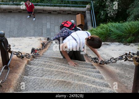 Westeuropäische Tourismusfrau steigt steile Stufen, die in eine Steinwand auf dem Huashan Berg / Berg Hua / Berg Hua in der Nähe von Huayin, Weinan, China, VR China gehauen werden. (125) Stockfoto