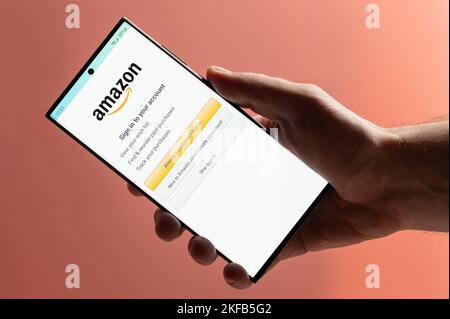 New york, USA - 10. November 2022: Melden Sie sich für Amazon Shopping auf dem Smartphone mit der Hand Nahaufnahme auf rosa Hintergrund Stockfoto