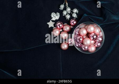 Weihnachtskomposition aus rosafarbenen Weihnachtsbaumkugeln, silbernem Stern und getrockneten Blumen auf dunklem Hintergrund. Vorbereitung auf die Feiertage. Stockfoto
