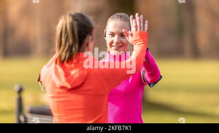 Zwei Freundinnen unterstützen sich gegenseitig und geben nach einem Lauf High-Five. Stockfoto