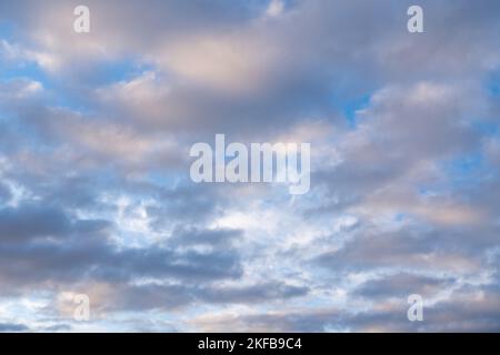 Wunderschöner Sonnenuntergang- oder Sonnenaufgangshimmel, der dunkelblaue und blassrosa Wolken erhellt. Wolkiger Himmel, um auf Ihren Fotos zu überlagern. Stockfoto