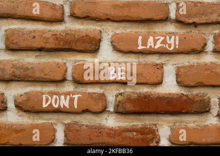 Motivierend und nicht faul Symbol sein. Konzeptwörter sind nicht faul auf Ziegelwänden. Schöne Backsteinmauer Hintergrund. Geschäft sei nicht faul Konzept. Stockfoto