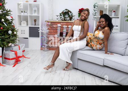 Zwei hübsch gekleidete afrikanische Frauen erwarten die Besucher am Weihnachtstag. Stockfoto