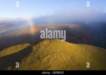 Zwei Wanderer auf dem Gipfel Dufton Pike mit einem Regenbogen über ihnen, Eden Valley, Cumbria, Großbritannien Stockfoto