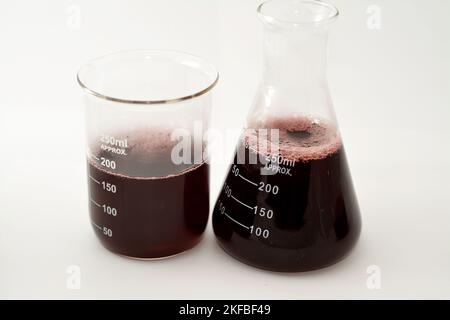 Ein Laborsatz aus konischen und volumetrischen Kolben, der nach einer wissenschaftlichen Experimentforschung dunkelrote Flüssigkeit mit Blasen enthält Stockfoto
