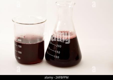 Ein Laborsatz aus konischen und volumetrischen Kolben, der nach einer wissenschaftlichen Experimentforschung dunkelrote Flüssigkeit mit Blasen enthält Stockfoto