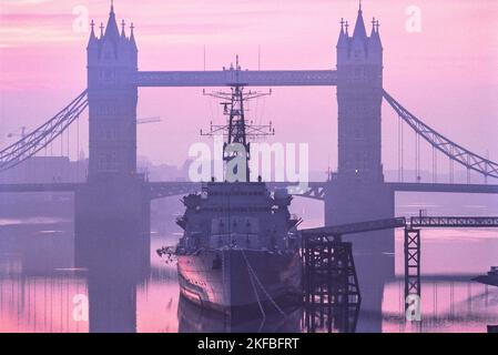 London River Thames, Blick bei Sonnenaufgang auf die Tower Bridge mit der HMS Belfast an ihrem permanenten Liegeplatz in der Themse im Vordergrund, London, England, Großbritannien Stockfoto