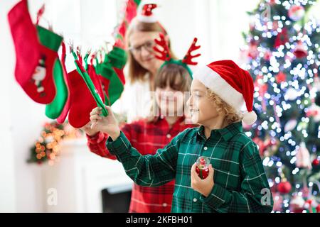 Kinder eröffnen Weihnachtsgeschenke. Kind auf der Suche nach Süßigkeiten und Geschenken im Adventskalender am Wintermorgen. Geschmückter Weihnachtsbaum Stockfoto