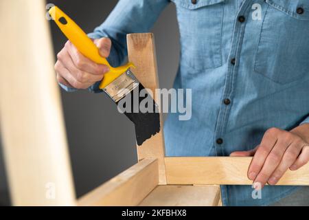 Junge Frauen bereiten sich darauf vor, eine Stube für Kinder als Hobbyhausverbesserung wiederherzustellen. Auf einem überdachten Tisch. Malen mit Pinsel Stockfoto