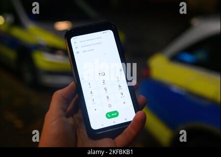 Hamburg, Deutschland. 17.. November 2022. Die Notrufnummer „110“ wird auf einem Smartphone eingegeben, das vor zwei Patrouillenautos gehalten wird. Aufgrund von Störungen im Mobilfunknetz erhielten die Behörden in Berlin, Bremen und Hamburg am 17.11.2022 immer mehr Tipps, dass der Notruf nicht erreichbar sei. Quelle: Jonas Walzberg/dpa/Alamy Live News Stockfoto