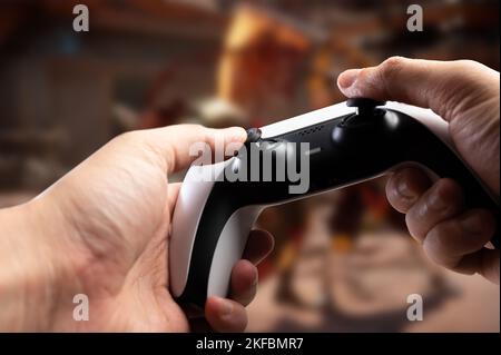 Nahaufnahme. Modernes Gamepad GAM22ICB in den Händen eines Spielers. Gamer spielt ein Videospiel. Lustige Abenteuer, Sport, pädagogische Online-Spiele. Wettbewerbe, Stockfoto