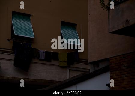 Die Fenster sind durch Vorhänge und Kleidung an der Fassade eines Wohnhauses geschlossen Stockfoto