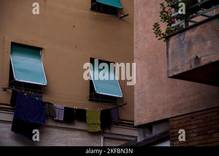 Die Fenster sind durch Vorhänge und Kleidung an der Fassade eines Wohnhauses geschlossen Stockfoto