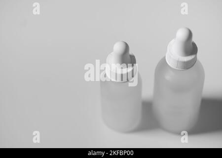 Draufsicht auf zwei leere Tropfflaschen aus durchsichtigem Glas. Flaschen unterschiedlicher Größe auf weißem Hintergrund. Horizontaler Beauty-Mockup- und Kopierbereich. Stockfoto