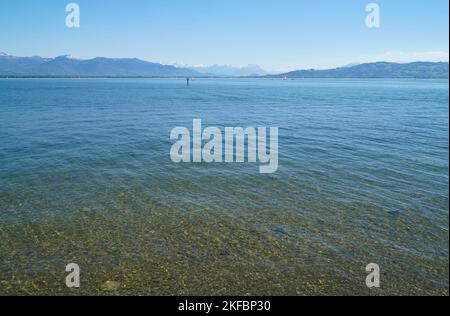 Wunderschönes blaues Wasser des Bodensees mit den Alpen im Hintergrund, von den Ufern der Insel Lindau an einem sonnigen Frühlingstag gesehen, Deutschland Stockfoto