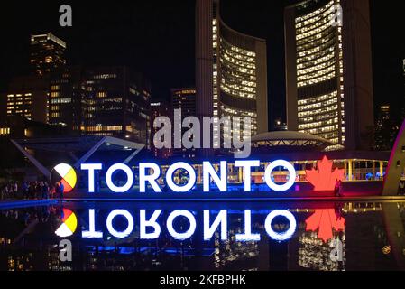 Toronto, Kanada - 11. August 2022: Toronto-Schild leuchtet nachts auf dem Nathan Phillips Square mit dem Rathaus im Hintergrund. Stockfoto