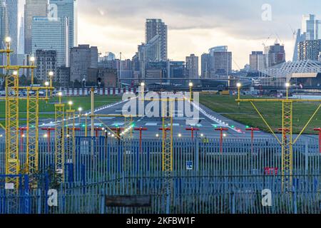 Eine leere Start- und Landebahn bei Sonnenuntergang, mit Blick auf Canary Wharf, London City Airport. Stockfoto