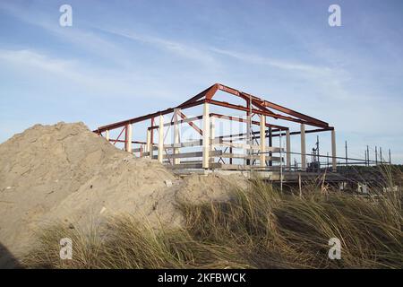 Skelettrahmen, gerahmte Struktur eines Hauses, das in den Sanddünen gebaut wird. Stahlträger. Sandhaufen, Marrammgras. Herbst, November, Niederlande, Bergen Stockfoto