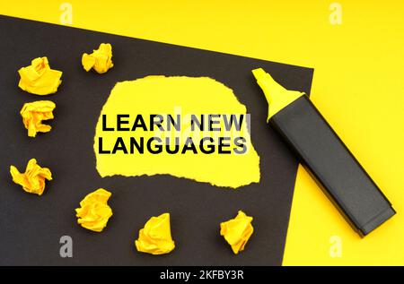 Geschäfts- und Bildungskonzept. Auf einem gelben Hintergrund liegt ein schwarzes Blatt, auf dem gelbes Papier mit der Aufschrift - Learn New Languages liegt Stockfoto