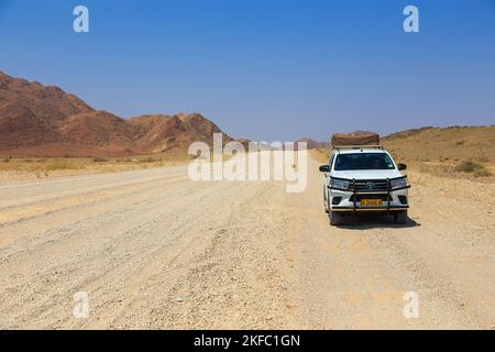 Sesriem, Naukluft , Namibia - 01. Oktober 2018: Typischer 4x4 Mietwagen in Namibia mit Campingausrüstung und einem Dachzelt, das auf einer unbefestigten Straße unterwegs ist Stockfoto