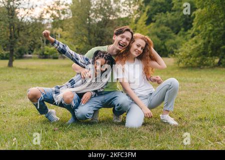 Fröhlicher Junge und zwei Mädchen erstellen trendige Inhalte auf der mobilen App, um sie in den sozialen Medien zu teilen. Gen Z-Unterhaltung. Mobiltelefonkommunikation. Video live Stockfoto