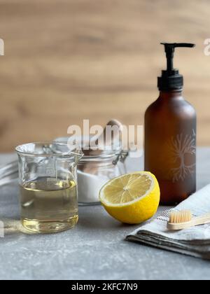 Natürliche Reinigungsmittel - Backpulver, Zitrone, Essig und Zahnbürste aus Holz. Hausgemachte umweltfreundliche Reinigungsprodukte. Stockfoto